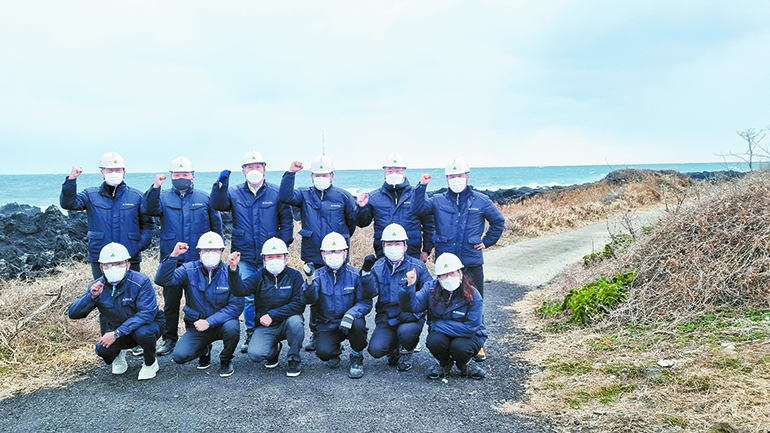 Site workers taking a group photo against the coast of Hallym-eup, Jeju as background, where 18 5.56MW offshore wind power generators will be installed
